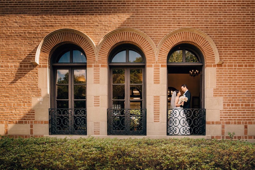 bride and groom standing in the window of the Cohen House at Rice University