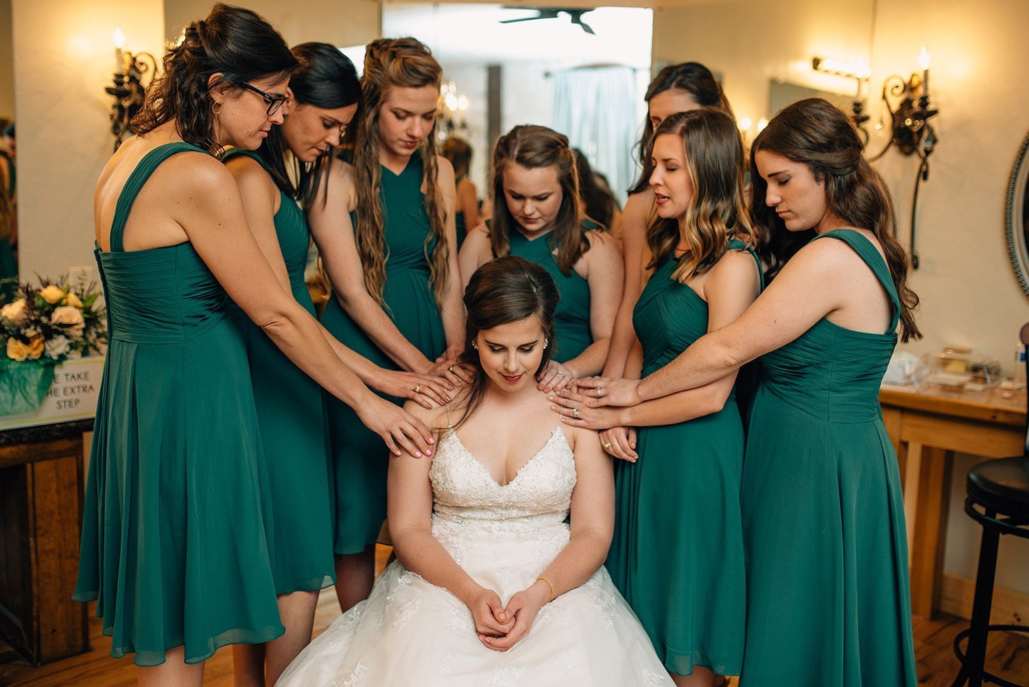 bridesmaids praying for bride in bridal room before wedding at the springs event center