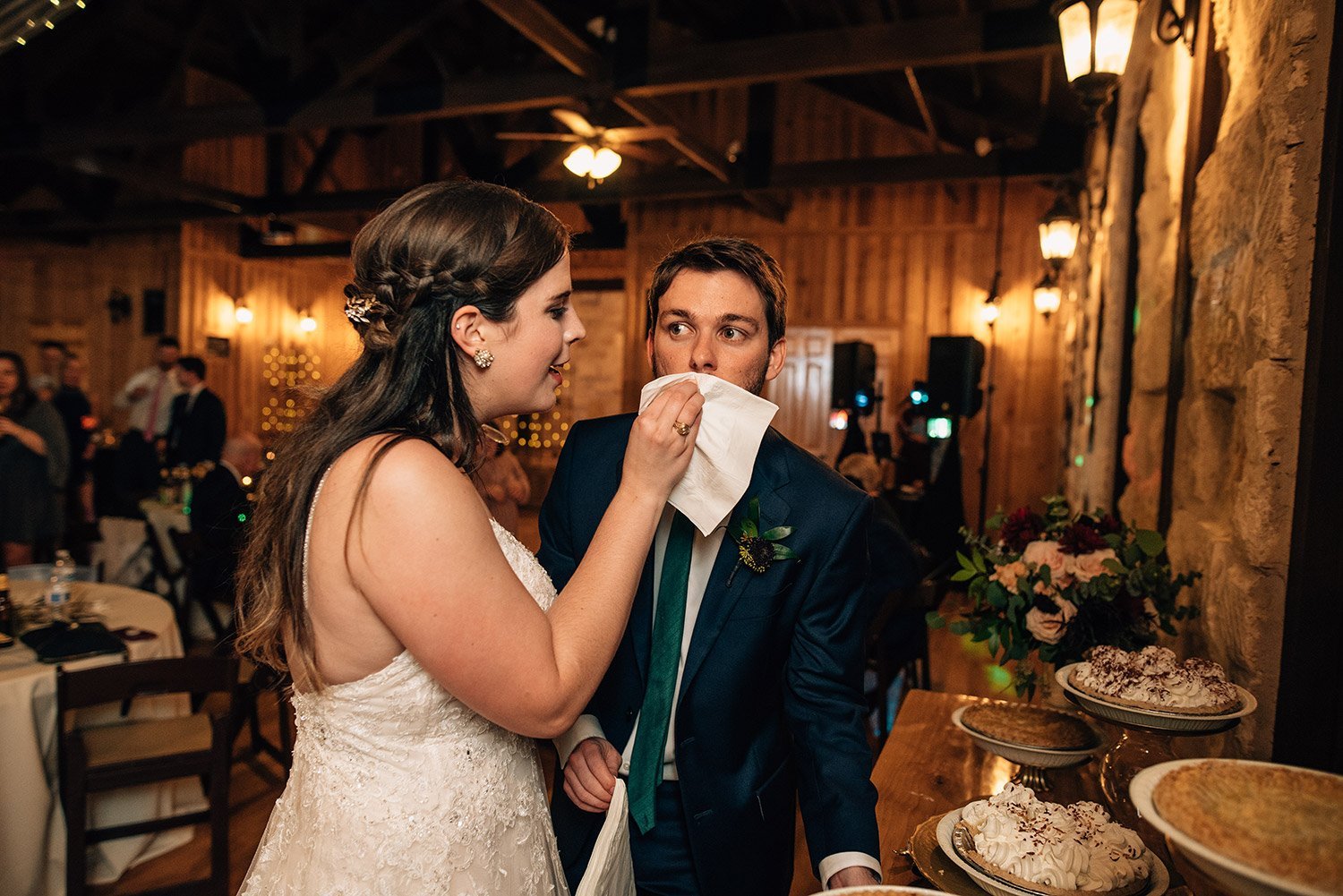 bride wiping grooms mouth after cutting pie instead of cake