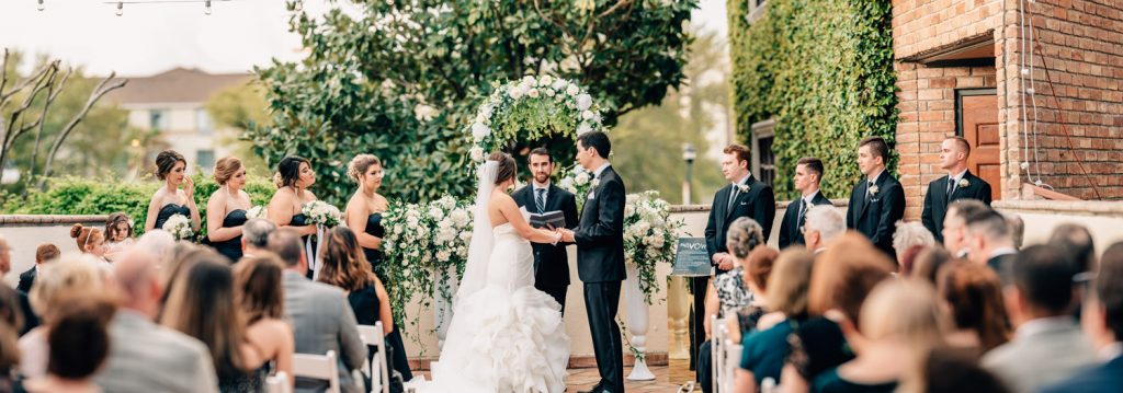 wide shot of guests, bridal party, and bride and groom standing for their wedding ceremony at the gallery houston