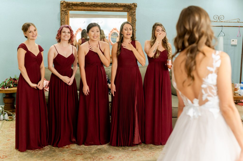 bridesmaids see bride in her wedding dress for first time in the bridal suite
